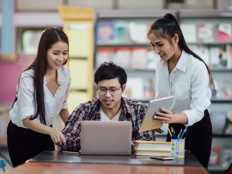 Young students learning,library bookshelves on background
